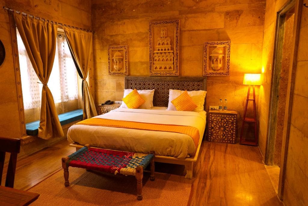 A room lit warm in the evening, with a wooden bench at the foot of the bed